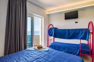 1 dormitorio con 2 camas, TV y ventana en Carlton Hotel Riviera en Cefalú