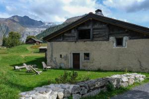 an old house in a field with mountains in the background at Refuge Margot in Chamonix-Mont-Blanc