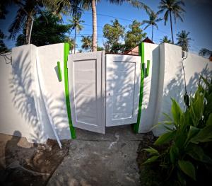 zwei weiße Türen mit grünen Griffen auf einem Zaun in der Unterkunft Kaktus bungalow 4 in Gili Air