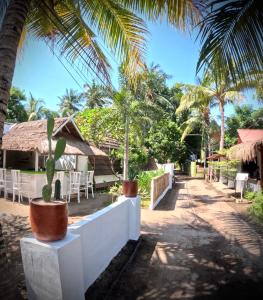 ein Resort mit Palmen, Tischen und Stühlen in der Unterkunft Kaktus bungalow 4 in Gili Air