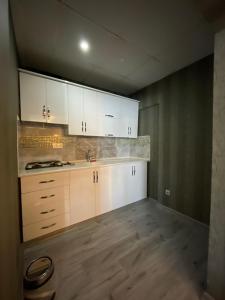 uma cozinha com armários brancos e piso em madeira em deperlas em Atakum