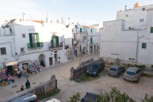 una calle de la ciudad con coches estacionados frente a los edificios en Casa Sorrentino, en Cisternino