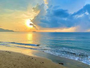una puesta de sol en una playa con el océano en The View Hotel en Cam Lâm