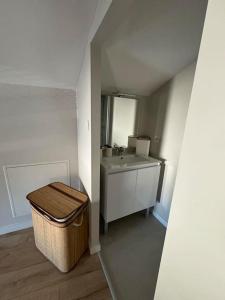 a bathroom with a sink and a mirror and a trash can at Appartement duplex 4-6 personnes in Cerizay +1 photo