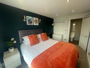 The Marlborough Sea View Holiday Apartments في سكرابورو: غرفة نوم بسرير كبير مع بطانية برتقالية