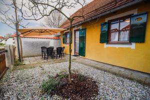 ein gelbes Haus mit einem Tisch, Stühlen und einem Regenschirm in der Unterkunft Spa House Alenka Terme Čatež in Čatež ob Savi