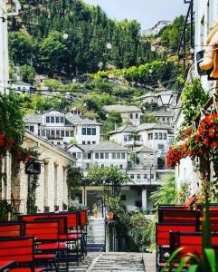 a group of red benches on a hill with houses at Sofia's modern apartment in Gjirokastër