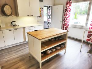 a kitchen with white cabinets and a wooden island at Wanha Koulu Tahko Onnela, 4mh, Palju, Sauna, Tupakeittiö, Wifi, Liikuntasali, RinteetSpaRavintola 6km, Lemmikit OK, Edukas in Reittiö