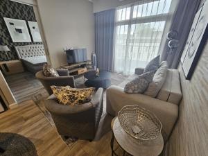 ein Wohnzimmer mit einem Sofa, Stühlen und einem TV in der Unterkunft Capital Trilogy Apartments in Pretoria