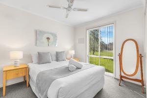 a white bedroom with a bed and a window at Madigan Cottages - Settlers Cottage in Lovedale