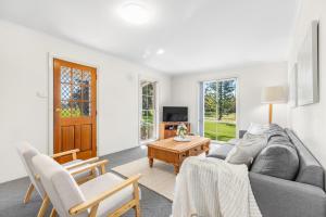 a living room with a gray couch and a table at Madigan Cottages - Settlers Cottage in Lovedale