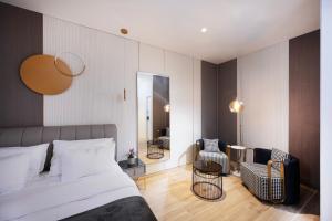 a bedroom with a bed and two chairs and a mirror at Allenbeach TLV- apart Hotel- Adults only in Tel Aviv