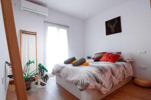 Un dormitorio con una cama con almohadas rojas y una ventana en EDomus Feria y Flamenco, en Sevilla