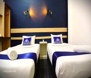 a room with two beds with blue and white at Alia Express Green Mango, Kota Bharu in Kota Bharu