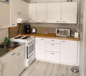 a white kitchen with white cabinets and a microwave at Teachers Apartment, Tahko, TV, Sauna, Shower, WiFI, Pets OK, Budget, Wanha Koulu Tahkovuori in Reittiö