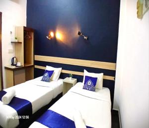 two beds in a room with blue and white at Alia Express Green Mango, Kota Bharu in Kota Bharu