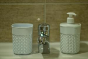 duas chávenas sentadas num lavatório ao lado de uma torneira em AMD UNION Caffe & Rooms em Kruševac