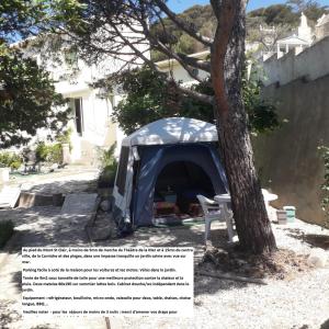 una tenda è posizionata accanto a un albero. di Deux tentes confortables dans un joli jardin idéalement situé a Sète