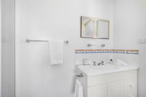 Un baño blanco con lavabo y espejo. en Madigan Cottages - The Homestead, en Lovedale 20 fotos más