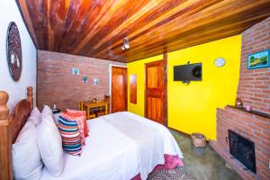 a bedroom with a white bed and a yellow wall at Chalés Recanto da cachoeira in Monte Verde