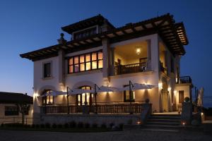 uma grande casa branca à noite com luzes em Hotel El Rosal de Cudillero em Cudillero