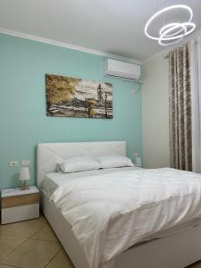 sypialnia z białym łóżkiem i niebieską ścianą w obiekcie Laert's Appartement w Tiranie