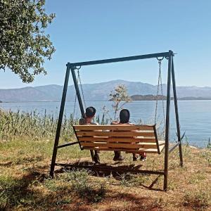 two people sitting on a swing by the water at Eses Camping in Muğla