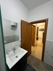 W łazience znajduje się biała umywalka i lustro. w obiekcie Laert's Appartement w Tiranie
