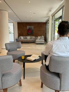 un hombre sentado en una silla en una sala de estar en Angela Downtown Hotel en Rodas