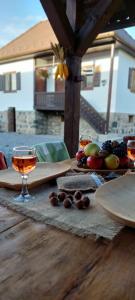 a table with a glass of wine and fruit on it at Boglárka Vendégház in Morăreni