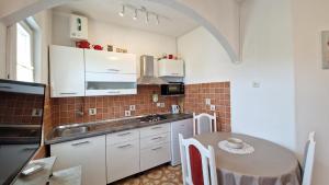 eine Küche mit weißen Schränken und einem Tisch darin in der Unterkunft Apartments Godena in Rovinj
