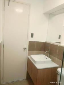 y baño con lavabo blanco y espejo. en REI Condotel Arezzo place Davao, en Davao City