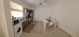 una piccola cucina con tavolo e lavatrice di Modern-Studio apartment in Qawra Malta a San Pawl il-Baħar