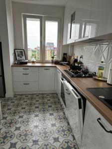 a kitchen with white cabinets and a tile floor at Nocleg na doby S 61 ROAD in Suwałki