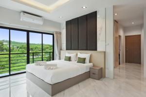 a bedroom with a large bed and a large window at De Piraya residence in Ban Bo Sai Klang