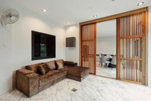 uma sala de estar com um sofá castanho e uma sala de jantar em De Piraya residence em Ban Bo Sai Klang