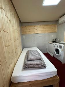 um pequeno quarto com uma cama e uma máquina de lavar roupa em Seoul Station R Guesthouse em Seul