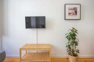 un televisor en una pared con una mesa y una planta en Formosa79 Apartments by Guestify en Oporto
