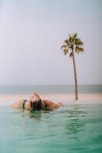 加的斯的住宿－Cádiz Bahía by QHotels，躺在棕榈树旁边的水里的妇女