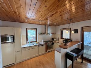 una cocina con armarios blancos y techos de madera. en La Villa des Vennes, en Heure