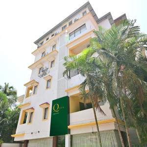 a tall building with a palm tree in front of it at Q lite Calangute in Calangute