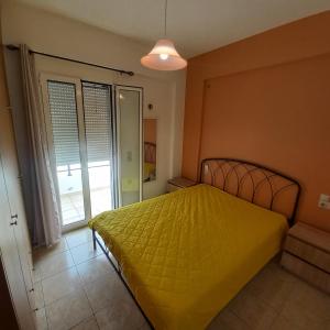 a bedroom with a yellow bed and a sliding glass door at Central Rooms in Makry Gialos