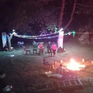穆拉的住宿－Eses Camping，一群人晚上站在 ⁇ 火旁