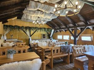 een restaurant met houten tafels en stoelen en een kroonluchter bij Osrodek Wypoczynkowy Lesniczówka & Elias SPA in Istebna