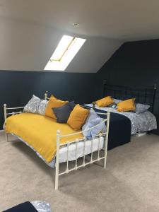 Duas camas com almofadas amarelas e azuis num quarto em Oxfordshire Village Apartment em Rotherfield Peppard