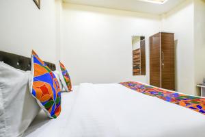 FabHotel Crown Park في إندوري: غرفة نوم مع سرير أبيض مع وسائد ملونة