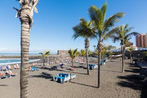 a beach with palm trees and a crowd of people at OkStay Apt Bencomo 50 m from the beach in Puerto de la Cruz