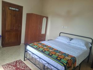 1 dormitorio con 1 cama y armario de madera en Cozy Escape in Accra by Manna Hospital, en Accra