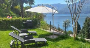 un grupo de sillas y una sombrilla en el césped en Casa le Palme, en Pino Lago Maggiore