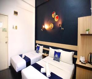 two beds in a hotel room with baseballabilia on the wall at Alia Express Green Mango, Kota Bharu in Kota Bharu